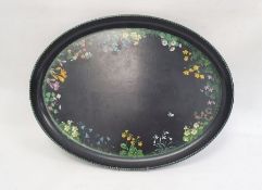 Papiermache tray of oval form, decorated with wild flowers, on a black ground, 51cm long, and two