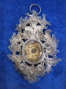 Victorian silver filigree reliquary pendant with central oval glass enclosing writing on paper