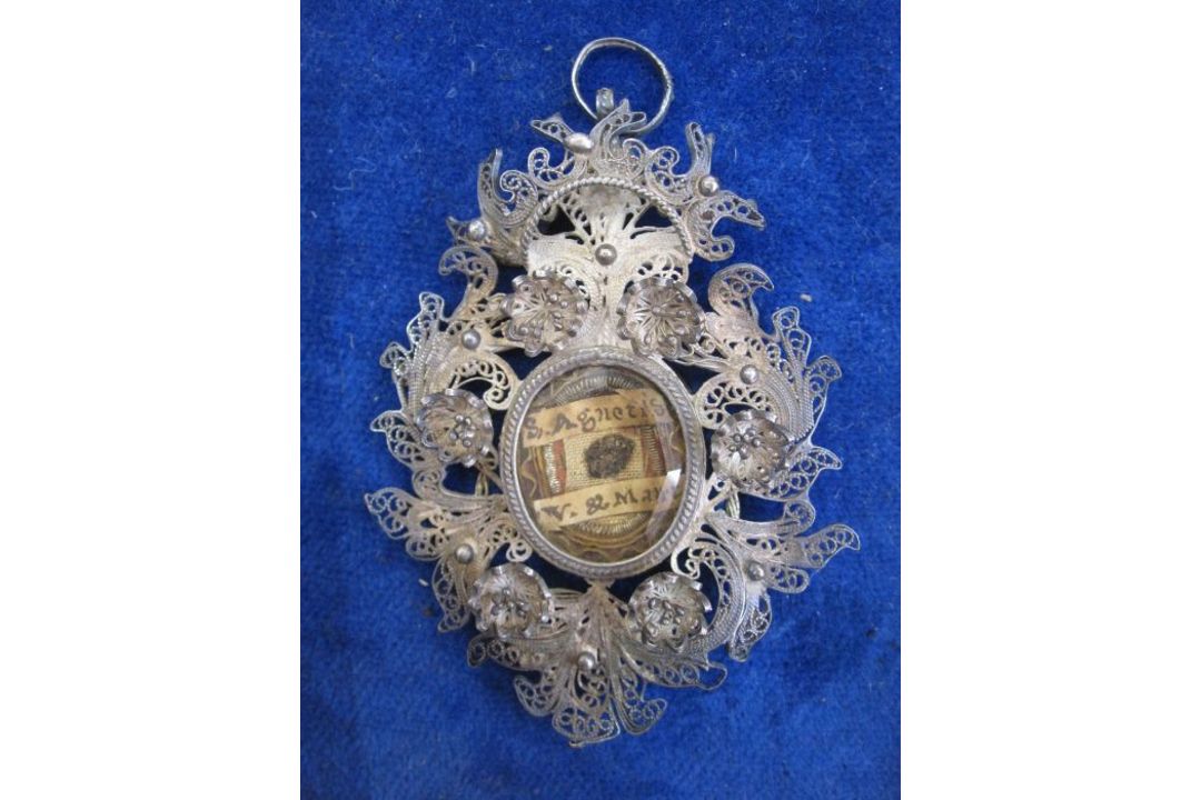Victorian silver filigree reliquary pendant with central oval glass enclosing writing on paper - Image 1 of 2