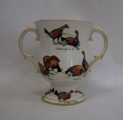 Ceramic two-handled trophy cup decorated with fighting birds 'A Challenge', 'A Knock Down Blow',