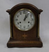 Oak-cased mantel clock with arched top, Arabic numerals to the dial, on plinth base