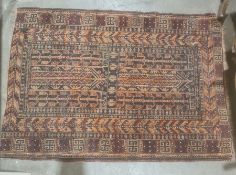 Eastern rug with black ground, red, orange and cream decoration, 120cm x 86cm