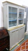 Painted cabinet with moulded corners above two glazed doors enclosing shelves, the painted base of