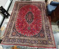 Eastern-style rug with central medallion on a red ground foliate decorated field, navy ground