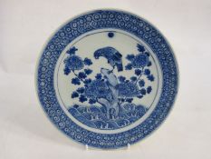 Blue and white porcelain plaque with bird of prey perched on a rocky outcrop, amidst waves, 26cm