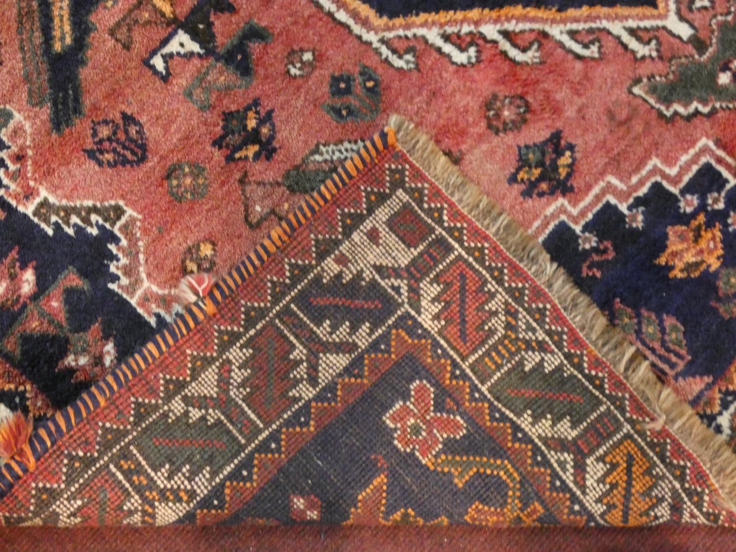 A Persian carpet with triple hooked central medallions with stylised bird motifs on the madder - Image 4 of 4