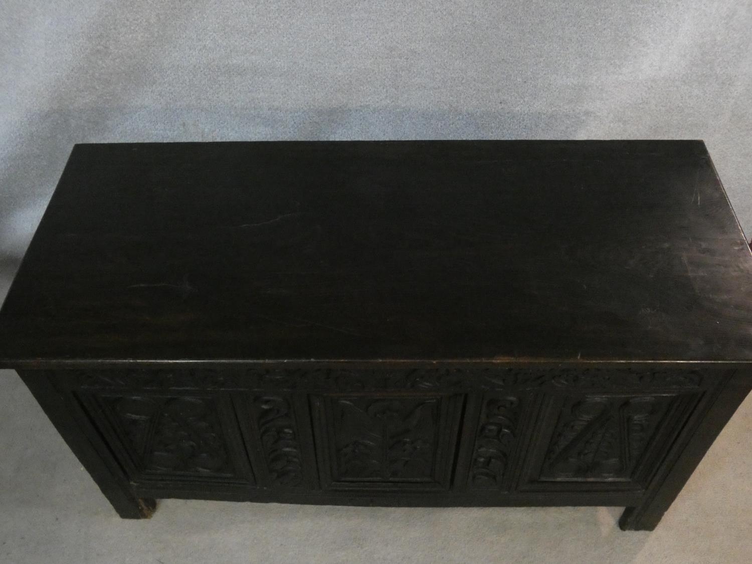 An antique country oak coffer with hinged lid above floral carved panels on block feet. H.75 L.136 - Image 3 of 8
