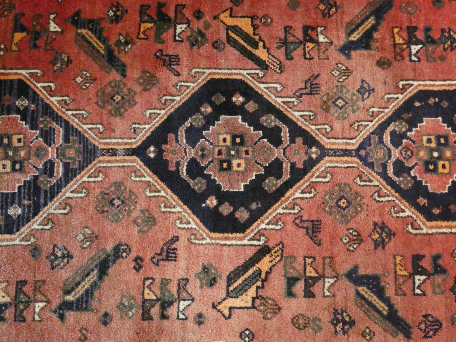 A Persian carpet with triple hooked central medallions with stylised bird motifs on the madder - Image 2 of 4