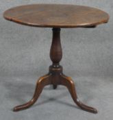 A Georgian oak tilt top table on baluster pedestal tripod supports. H.75cm (top in need of some