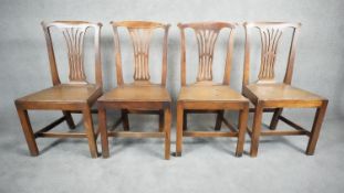 A set of four Georgian country oak pierced splat back dining chairs with panel seats on square