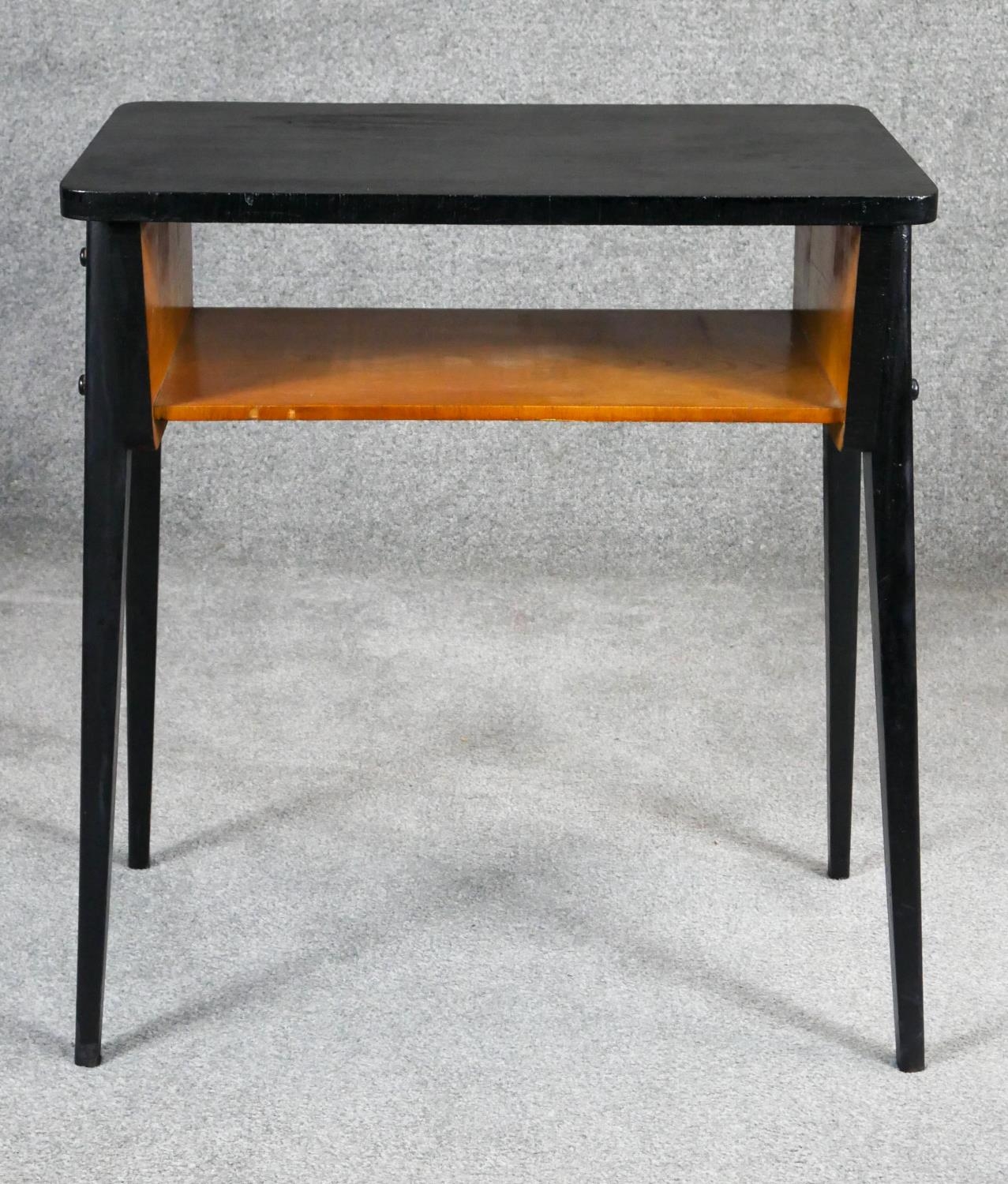 A retro vintage ebonised magazine table on splay supports. H.69 W.62 D.39cm