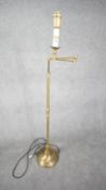 A contemporary brushed brass swing arm height adjustable floor lamp with circular base. Two pin