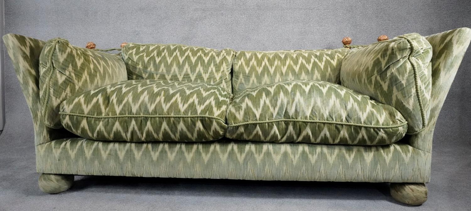 A Knole sofa in cut velour upholstery the drop ends with carved giltwood finials raised on bun feet.