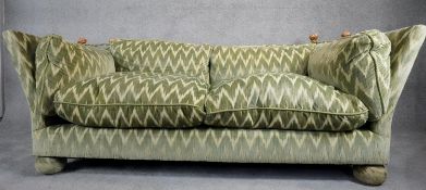 A Knole sofa in cut velour upholstery the drop ends with carved giltwood finials raised on bun feet.