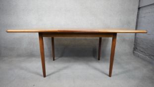 A 1960's vintage Meredew teak dining table with integral fold out central leaf and maker's label