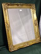 A MODERN GILT FRAMED WALL MIRROR 75 X 65 CM