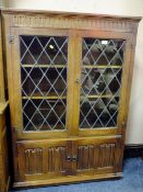 AN OAK LEADED AND GLAZERS BOOKCASE WITH LINENFOLD DOORS TO THE BASE H-136.5 W-97 CM