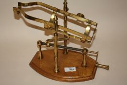 A BRASS WINE DECANTING CRADLE ON WOODEN PLINTH