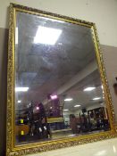 A LARGE MODERN GILT FRAMED WALL MIRROR 130 X 99 CM