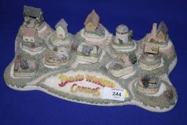A COLLECTION OF DAVID WINTER CAMEO COTTAGE FIGURES ON DISPLAY STAND