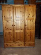 A PINE TRIPLE DOOR, THREE DRAWER WARDROBE