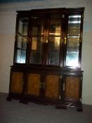 A GLASS SHELVED MIRROR BACKED BREAKFRONT WALL UNIT