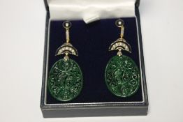 A PAIR OF OVAL SHAPED PATTERNED JADE DROP EARRINGS SET WITH DIAMONDS AND INLAID WITH BLACK ENAMEL,