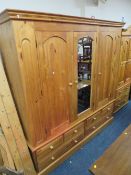 A LARGE PINE TRIPLE WARDROBE WITH CENTRAL MIRRORED DOOR AND 6 DRAWERS BELOW H 212 CMW 202 CM