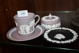 A WEDGWOOD LILAC JASPERWARE CUP AND SAUCER AND TRINKET BOWL, TOGETHER WITH A BLACK JASPERWARE PIN