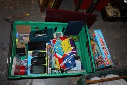 A TRAY OF BOARD GAMES ETC. TOGETHER WITH AN AMAZON KINDLE, MOBILE PHONES ETC.