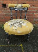 AN EDWARDIAN EBONISED LOW CHAIR WITH TURNED SPINDLES