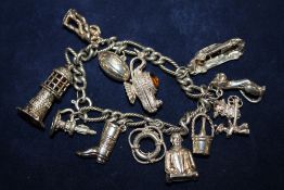 A SILVER CHARM BRACELET WITH ASSORTED CHARMS - APPROX 54.1G