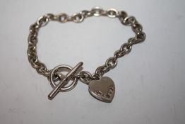 A LADIES SILVER BRACELET WITH GEM SET HEART FOB
