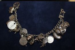 A SILVER CHARM BRACELET WITH ASSORTED CHARMS - APPROX 64.2G