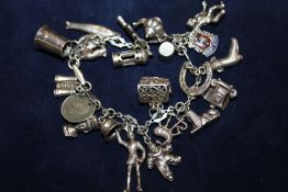A SILVER CHARM BRACELET WITH ASSORTED CHARMS - APPROX 54.7G