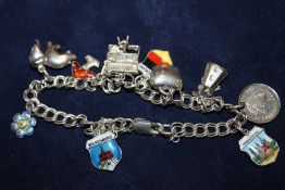 A SILVER CHARM BRACELET WITH ASSORTED CHARMS TO INCLUDE ENAMEL EXAMPLES - APPROX 19.9G