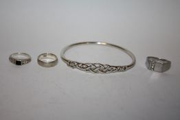 A STERLING SILVER BANGLE AND THREE SILVER DRESS RINGS