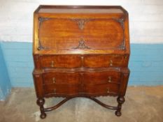 AN ANTIQUE SERPENTINE FRONTED OAK LEATHER INLAID BUREAU