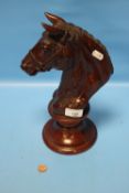 A CARVED WOODEN HORSE'S HEAD ON PLINTH