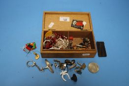 A WOODEN CIGARETTE BOX CONTAINING JEWELLERY COINS AND CUFFLINKS ETC.
