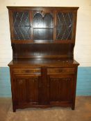 AN OAK DISPLAY WALL UNIT WITH LEADED GLASS AND LINENFOLD DESIGN