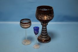 A LARGE BOHEMIAN RUBY OVERLAY GLASS GOBLET WITH GRAPE AND VINE DECORATION TOGETHER WITH TWO OTHER