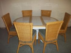 AN EXTENDING TILE TOPPED ROUND DINING SET TABLE AND SIX WICKER CHAIRS