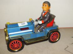 A VINTAGE BATTERY OPERATED TIN PLATE TOY MAN IN A CLASSIC CAR