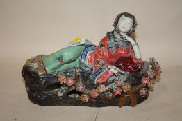 AN ORIENTAL CERAMIC RECLINING LADY HOLDING A BOOK