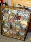 A WALL HANGING OAK LEADED GLAZED DISPLAY CASE CONTAINING VINTAGE JARS AND TINS, S/D