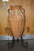 A LARGE TWIN HANDLED TERRACOTTA VASE ON CAST METAL STAND OVERALL HEIGHT - 93CM