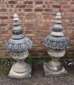 A PAIR OF LARGE STONE PEDESTAL URNS, supported on a squared foot leading to a solid swirling base,