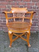 AN ANTIQUE OAK SWIVEL ARMCHAIR, with pierced back, the circular swivel seat raised on four