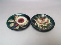 TWO MOORCROFT PIN DISHES, to include a 'Hellebore' pattern example, typical tubelined decoration,